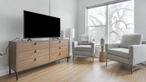 ein Wohnzimmer mit einem TV und 2 Stühlen in der Unterkunft Landing Modern Apartment with Amazing Amenities (ID1241X658) in Tower Grove