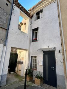 um edifício branco com uma porta preta numa rua em Studio Sanae em Lézignan-Corbières