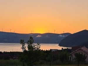 a sunset over a body of water with windmills at Od svitanja do sumraka in Golubac