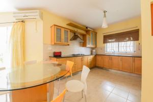 a kitchen with a glass table and white chairs at Pereybere Beach Villas in Pereybere