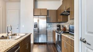 a kitchen with a stainless steel refrigerator and wooden cabinets at Landing Modern Apartment with Amazing Amenities (ID9245X93) in Irving