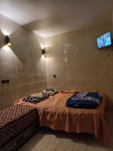 a bedroom with a bed with a tv on the wall at Moulay Idriss in Moulay Idriss Zerhoun