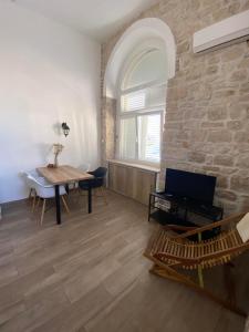 uma sala de estar com uma mesa e uma parede de pedra em Apartments Karuza Center of old town Vis em Vis