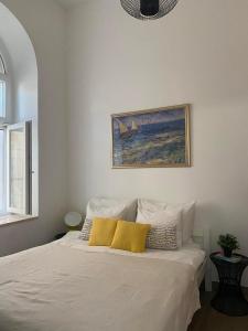 a bedroom with a white bed with two yellow pillows at Apartments Karuza Center of old town Vis in Vis