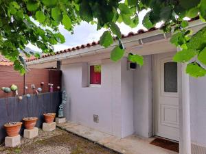 Biały dom z drzwiami i doniczkami w obiekcie Maison d'une chambre avec terrasse a Tarascon sur Ariege w mieście Tarascon-sur-Ariège