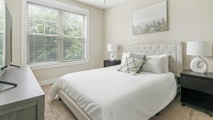 1 dormitorio blanco con 1 cama y 2 ventanas en Landing Modern Apartment with Amazing Amenities (ID2268X42), en Raleigh