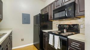 eine Küche mit einem schwarzen Herd und einem Kühlschrank in der Unterkunft Landing Modern Apartment with Amazing Amenities (ID4287X35) in Orlando