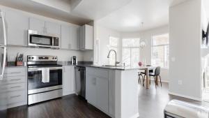 a white kitchen with white cabinets and a table at Landing Modern Apartment with Amazing Amenities (ID8102X91) in Phoenix