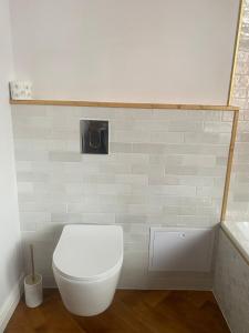 a bathroom with a toilet with a white tiled wall at Apartments PSD - Anny Łajming 1C in Słupsk