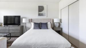 a white bedroom with a large bed and a tv at Landing Modern Apartment with Amazing Amenities (ID1357X457) in Portland