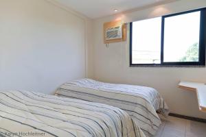 two beds in a room with two windows at Apartamento Porto Real Angra Dos Reis in Mangaratiba