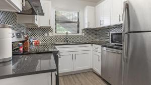 uma cozinha com armários brancos e um frigorífico de aço inoxidável em Landing Modern Apartment with Amazing Amenities (ID1204X607) em Charlotte