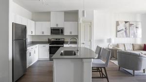 La cuisine est équipée de placards blancs et d'un réfrigérateur en acier inoxydable. dans l'établissement Landing Modern Apartment with Amazing Amenities (ID1377X491), à Pflugerville