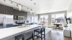 a kitchen with a large white counter and chairs at Landing Modern Apartment with Amazing Amenities (ID1960) in Denver