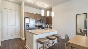 una cocina con una isla con taburetes y una mesa en Landing Modern Apartment with Amazing Amenities (ID8635X10) en Irving