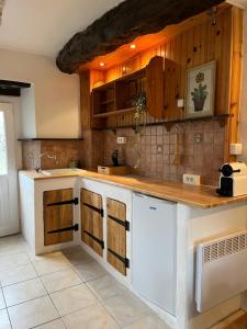 una cucina con bancone bianco e armadi in legno di Gite La Haye d'Armor a La Tiolais