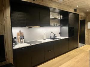 a kitchen with black cabinets and a sink at Kikut Alpin Lodge Ski in - Ski out in Geilo