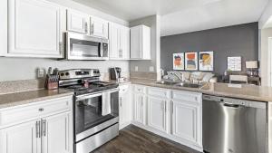 uma cozinha com armários brancos e electrodomésticos de aço inoxidável em Landing Modern Apartment with Amazing Amenities (ID4301X28) em Las Vegas