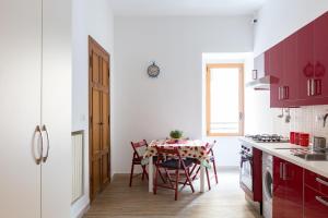 a kitchen with red cabinets and a table with chairs at New Flat Between The Vatican & Piazza del Popolo in Rome