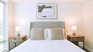 1 dormitorio con 1 cama blanca, 2 mesitas de noche y 2 lámparas en Landing Modern Apartment with Amazing Amenities (ID8092X98) en Orlando