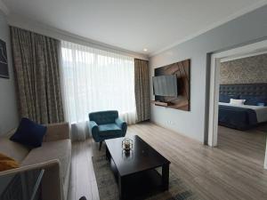 een woonkamer met een bank en een kamer met een bed bij Aparta Hotel Torres de Suites in Quito