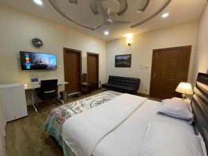a bedroom with a bed and a desk and a tv at Alpha Guest House in Rawalpindi