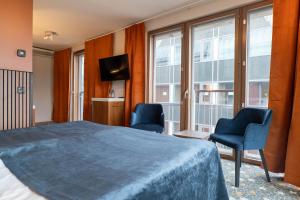 ein Hotelzimmer mit einem Bett, 2 Stühlen und einem TV in der Unterkunft ProfilHotels Opera in Göteborg