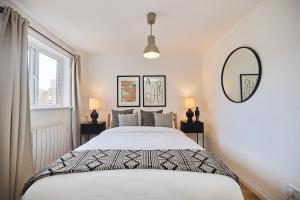Habitación blanca con cama y espejo en The Hackney Place - Spacious 1BDR Flat en Londres
