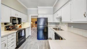 eine Küche mit weißen Schränken und einem schwarzen Kühlschrank in der Unterkunft Landing Modern Apartment with Amazing Amenities (ID9248) in Nashville