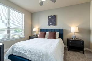 um quarto com uma cama azul com duas mesas de cabeceira e dois candeeiros em Landing Modern Apartment with Amazing Amenities (ID3876) em Carrollton