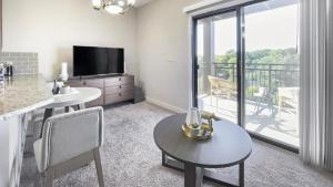 a living room with a table and a television and a balcony at Landing Modern Apartment with Amazing Amenities (ID1228X214) in Greenville