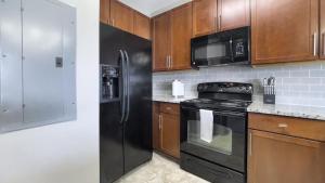 a kitchen with black appliances and wooden cabinets at Landing Modern Apartment with Amazing Amenities (ID1228X214) in Greenville