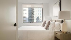 a bedroom with a white bed with a window at Landing Modern Apartment with Amazing Amenities (ID3117X83) in New York