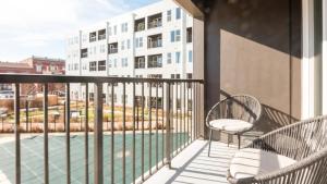 einen Balkon mit 2 Stühlen und Blick auf ein Gebäude in der Unterkunft Landing Modern Apartment with Amazing Amenities (ID5151X99) in Tower Grove