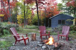 tres sillas sentadas alrededor de un fuego en un patio en Chalet Chic Shack - Un endroit paisible, en Frampton