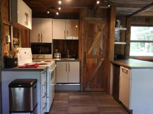 a kitchen with white appliances and a wooden door at Chalet Chic Shack - Un endroit paisible in Frampton
