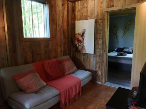 uma sala de estar com um sofá e um cobertor vermelho em Chalet Chic Shack - Un endroit paisible em Frampton