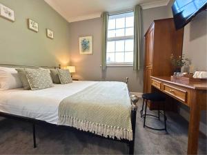 a bedroom with a bed and a desk and a television at The Windmill Hotel - Alford in Alford +38 photos