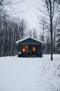 uma pequena casa na neve com luzes acesas em Chalet Chic Shack - Un endroit paisible em Frampton