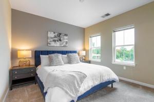 a bedroom with a blue bed and two windows at Landing Modern Apartment with Amazing Amenities (ID2286) in Ellicott City