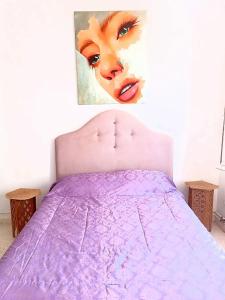 a bedroom with a purple bed with a painting on the wall at The Sidibou Said Story in Sidi Bou Saïd