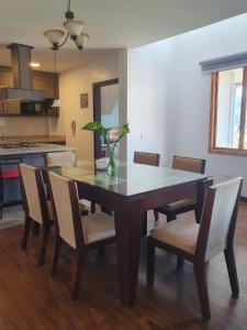 a dining room table with chairs and a vase with a plant at Adelita Departamento in Loja