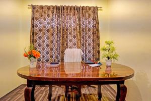 a wooden table with flowers and a curtain at OYO Lit Homestay in Srinagar