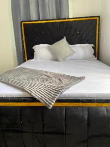 a bed with a wooden frame and white sheets and pillows at LuckySmallie 1-Bed Apartment in Goba Dar es Salaam in Dar es Salaam