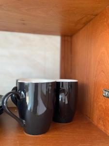 two black coffee cups sitting on a counter at LuckySmallie 1-Bed Apartment in Goba Dar es Salaam in Dar es Salaam