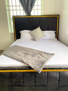 a bed with a black headboard and white pillows at LuckySmallie 1-Bed Apartment in Goba Dar es Salaam in Dar es Salaam