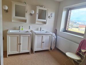 La salle de bains est pourvue de 2 lavabos blancs et d'une fenêtre. dans l'établissement Urlaubstraum, à Sankt Veit an der Glan