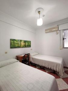 een kamer met drie bedden en een tafel erin bij Pension Hidalgo 1 in Utrera