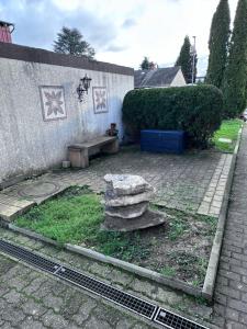 un jardín con un banco de piedra junto a una pared en Ferienwohnung Oberursel, en Oberursel