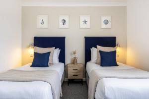 2 camas en una habitación de color azul y blanco en Inn For All Seasons en Redruth